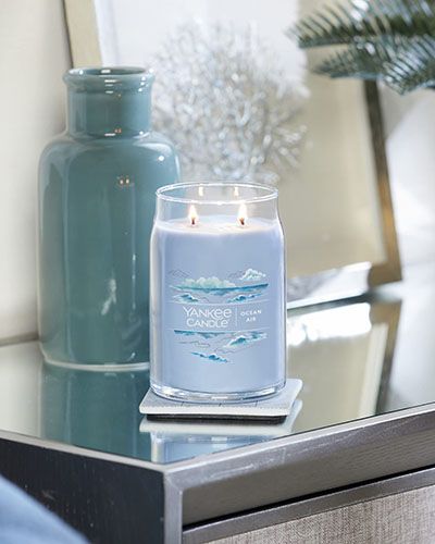 Bougie 'Ocean Air' de Yankee Candle allumée sur une table.
